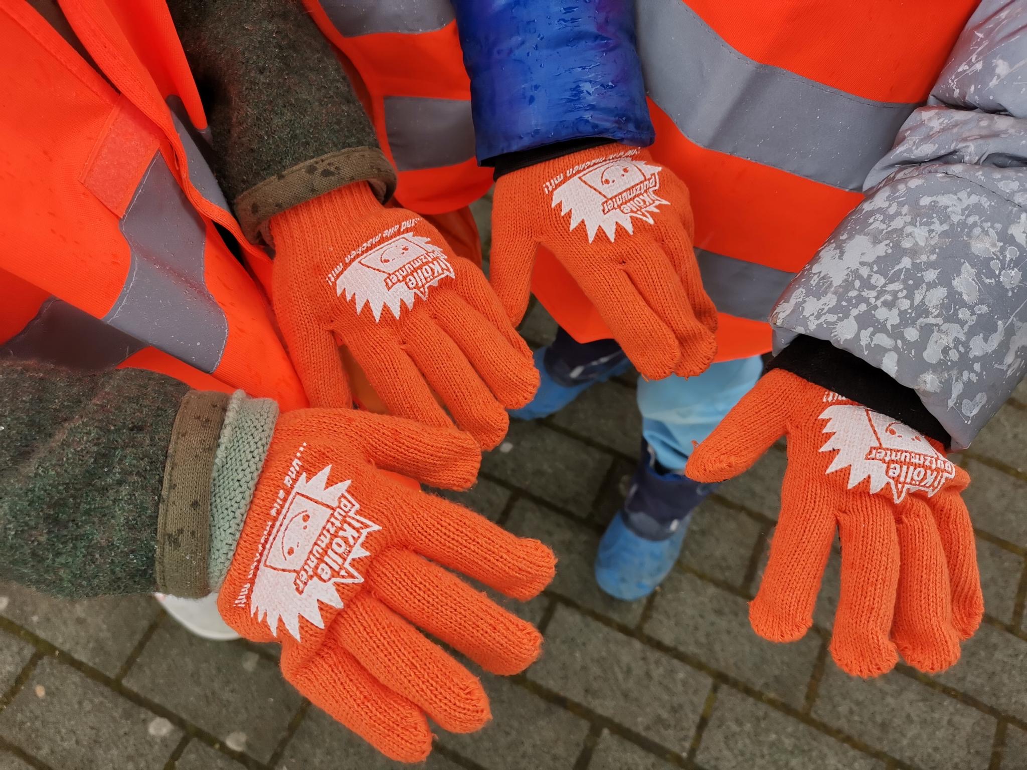 kinderhände mit orangefarbenen Handschuhen