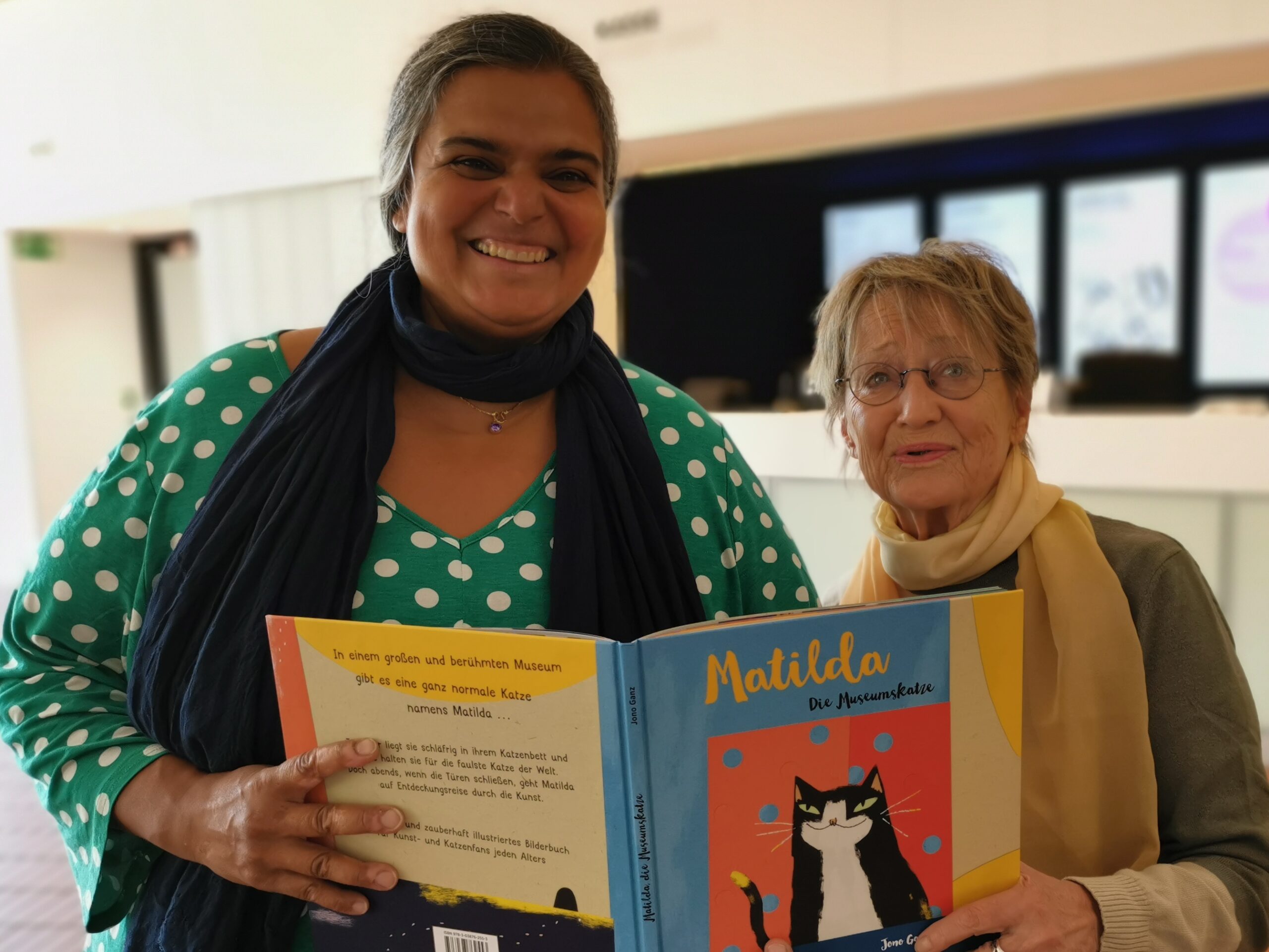 rpt Museumspädagogin und Vorleserin lächeln in die Kamera. Im Vordergrund ist der Buchrücken von Matilda zu sehen.